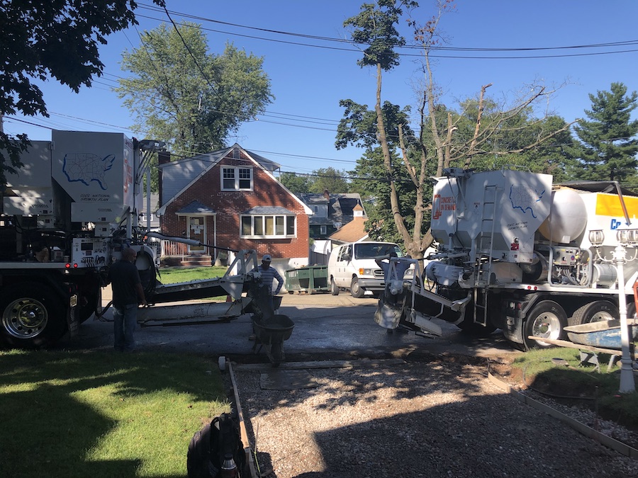 Crew finishing a residential concrete pour beside the on-site mixer truck